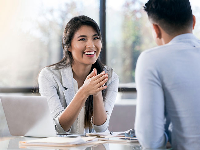 A woman smiling while talking to a business colleague
